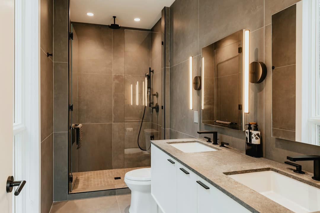 Moderne badkamer met inbouwspots en wandverlichting naast de spiegels